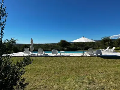 a pool with chairs and an umbrella and a statue at Complejo los Torres in Mina Clavero