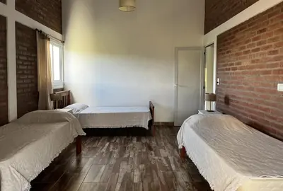 a room with three beds and a brick wall at Complejo los Torres in Mina Clavero