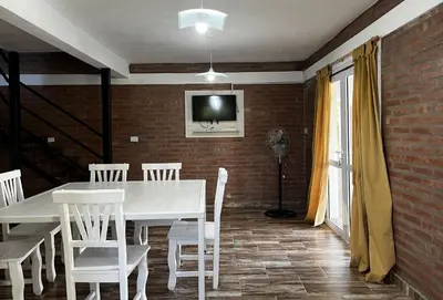 a dining room with a white table and white chairs at Complejo los Torres in Mina Clavero
