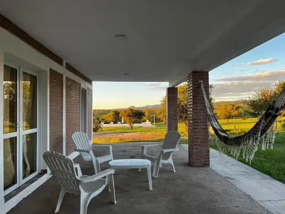 a porch with chairs and a table and a hammock at Complejo los Torres in Mina Clavero