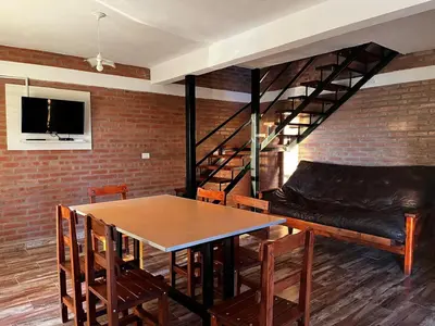 a dining room with a table and a couch and a loft at Complejo los Torres in Mina Clavero