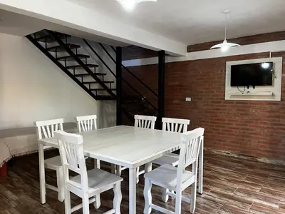 a dining room with a white table and white chairs at Complejo los Torres in Mina Clavero
