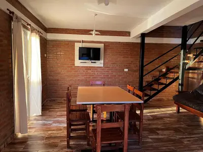 a dining room with a table and chairs and a brick wall at Complejo los Torres in Mina Clavero