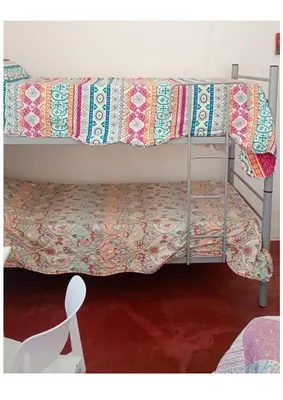 a bedroom with two bunk beds and a white chair at El Dpto de Gabicito IV in Cordoba