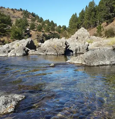 a river with rocks and trees in the background at Lavanda y Romero Villa Yacanto de Calamuchita in Villa Yacanto