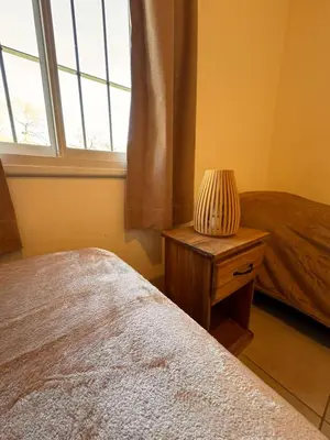 a bedroom with a bed and a lamp on a night stand at Entre Algarrobos - Cabañas con pileta y naturaleza in Villa de Las Rosas