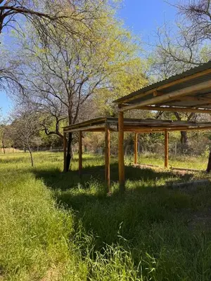 a wooden pavilion in a field with trees in the background at Entre Algarrobos - Cabañas con pileta y naturaleza in Villa de Las Rosas