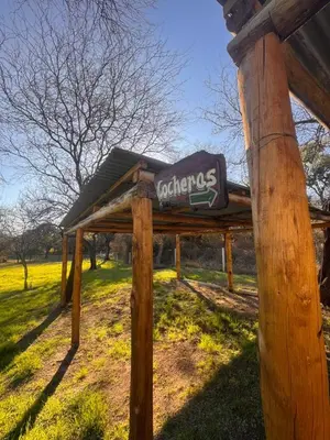 a sign on a wooden post in a field at Entre Algarrobos - Cabañas con pileta y naturaleza in Villa de Las Rosas
