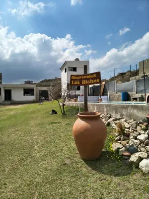 a sign in a yard with a large vase at Los Bichos in Estancia Vieja