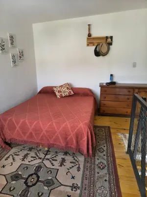 a bedroom with a bed with a red blanket and a rug at Los Bichos in Estancia Vieja