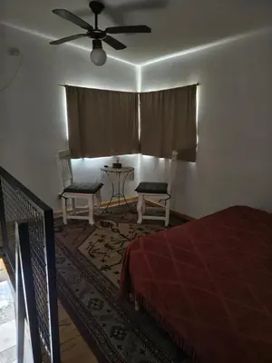 a bedroom with a bed and two chairs and a ceiling fan at Los Bichos in Estancia Vieja