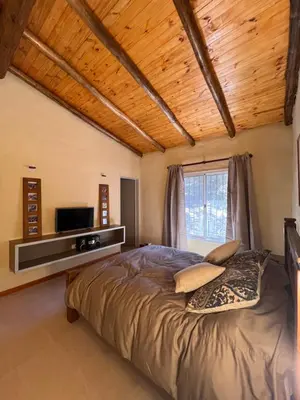 a bedroom with a bed with a television on the wall at Casa de Campo a metros del rio en las Sierras de Cordoba in Atos Pampa