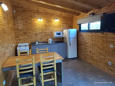 a kitchen with a table and a refrigerator at Cabanas del Solar in Los Reartes