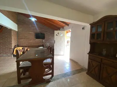 a dining room with a wooden table and a brick wall at Agosto 23 in Mina Clavero