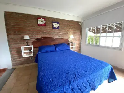a bedroom with a blue bed and a brick wall at Agosto 23 in Mina Clavero