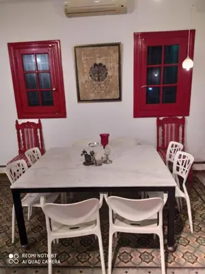 a dining room table with white chairs and red windows at La Victoria descanso Cordobes in Cordoba