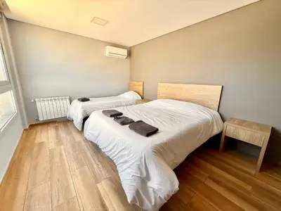 two beds in a room with wooden floors at Alojamiento entero para 8 personas Belgrano Park in Cordoba