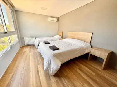 two beds in a small room with wooden floors at Alojamiento entero para 8 personas Belgrano Park in Cordoba