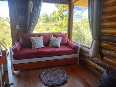 a red couch in a room with a large window at Refugio Doña Josefa, cabaña de montaña La Cumbrecita in La Cumbrecita