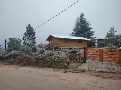a wooden cabin with a fence next to a dirt road at Refugio Doña Josefa, cabaña de montaña La Cumbrecita in La Cumbrecita