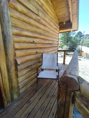 a wooden cabin with a chair on the deck at Refugio Doña Josefa, cabaña de montaña La Cumbrecita in La Cumbrecita