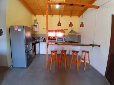 a kitchen with a counter with stools and a refrigerator at Sonidos del Silencio in Las Rabonas