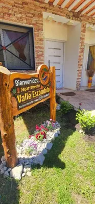 a sign in front of a house with flowers at departamentos valle escondido in Villa Yacanto