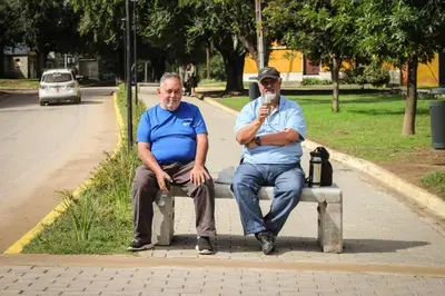 two men sitting on a bench in a park at departamentos valle escondido in Villa Yacanto