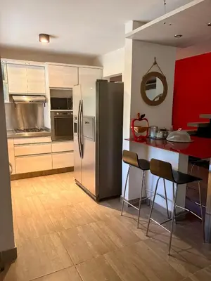 a kitchen with a refrigerator and a counter with chairs at Punta Serrana in La Paisanita
