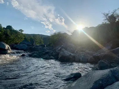 a river with rocks and the sun in the sky at Punta Serrana in La Paisanita