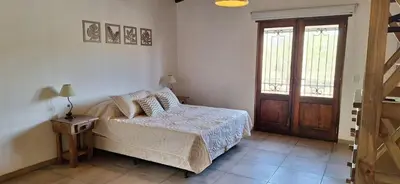 a bedroom with a bed and a wooden door at Habitare Departamentos in Los Reartes
