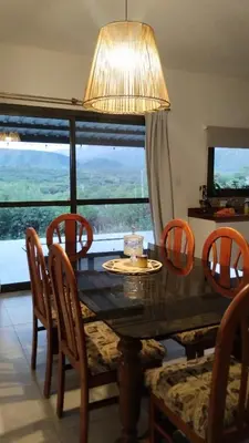 a dining room table with chairs and a large window at Sol & Río Refugio Serrano in Villa de Las Rosas