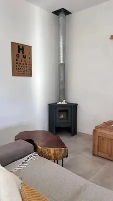 a living room with a wood stove and a couch at Sol & Río Refugio Serrano in Villa de Las Rosas