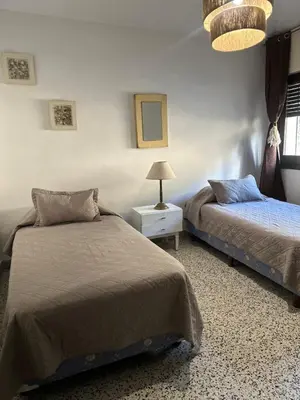 a bedroom with two beds and a table with a lamp at lacasadelamontaña L&E in Villa Carlos Paz