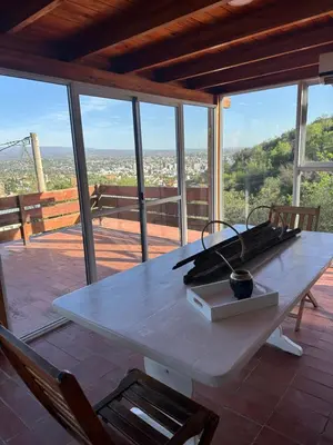 a large white table with two chairs on a patio at lacasadelamontaña L&E in Villa Carlos Paz