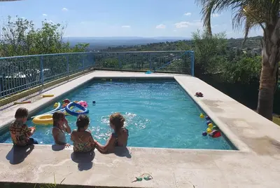 a group of people sitting around a swimming pool at Casa en las Sierras de Cordoba in Villa Parque Siquiman