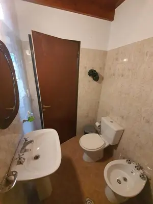 a bathroom with a white toilet and a sink at Casa en las Sierras de Cordoba in Villa Parque Siquiman