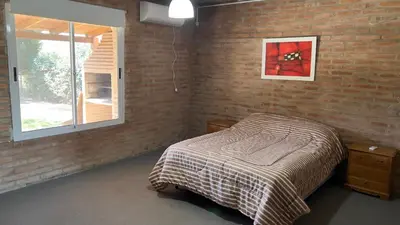 a bedroom with a bed and a brick wall at La Casona Dique Chico in Villa Anizacate