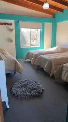 a room with three beds and a window at La Casona Dique Chico in Villa Anizacate