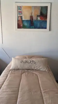 a bed in a bedroom with a painting on the wall at La Casona Dique Chico in Villa Anizacate