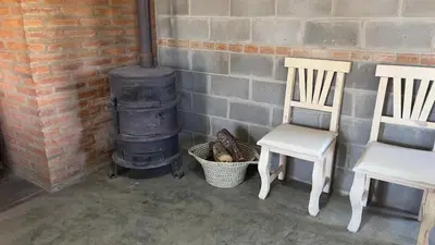 a couple of chairs and a wood stove at La Casona Dique Chico in Villa Anizacate
