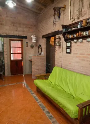 a living room with a green couch and a brick wall at Cabaña para 8 en Arroyo de los Patos in Arroyo de Los Patos