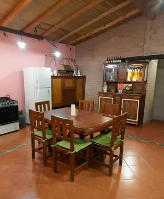 a kitchen with a wooden table with chairs and a refrigerator at Cabaña para 8 en Arroyo de los Patos in Arroyo de Los Patos