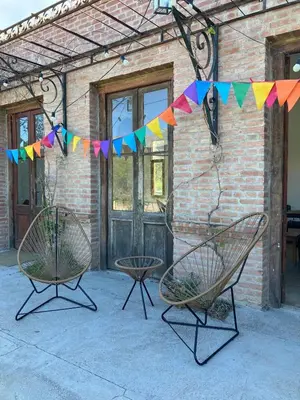two chairs and a table in front of a building with flags at Casa de Las Brujas Traslasierra in Los Molles