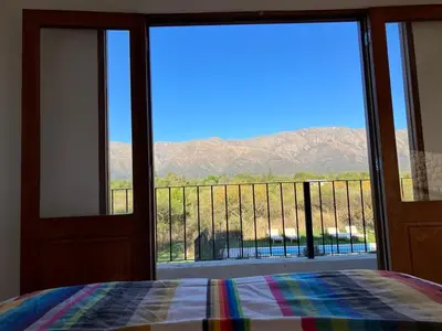 a bedroom with a view of the mountains through a sliding glass door at Casa de Las Brujas Traslasierra in Los Molles