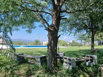 a park with benches under a tree next to a pool at cabaña Mirador in Bialet Massé