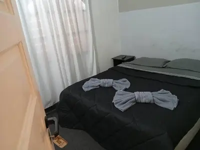 a bed with a black comforter with a bow tie on it at New POSADA SOL in Villa Carlos Paz