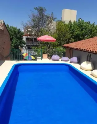a blue swimming pool with chairs and an umbrella at New POSADA SOL in Villa Carlos Paz
