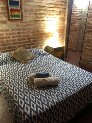 a bedroom with a bed with a blue and white blanket at Cabaña en el centro La Casona in Mina Clavero