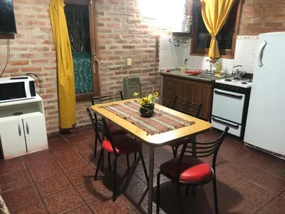 a kitchen with a table with chairs and a white refrigerator at Cabaña en el centro La Casona in Mina Clavero
